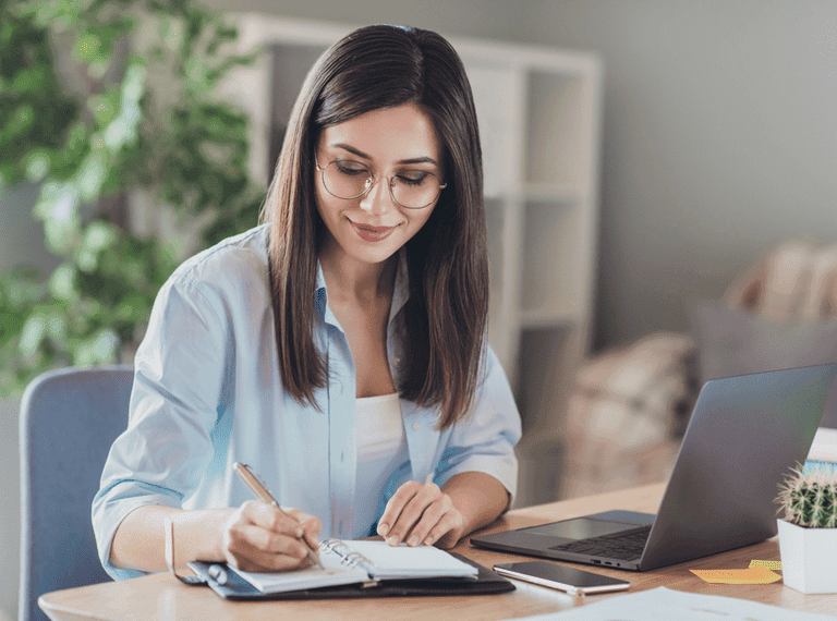 A woman sits at a desk, planning her CV.