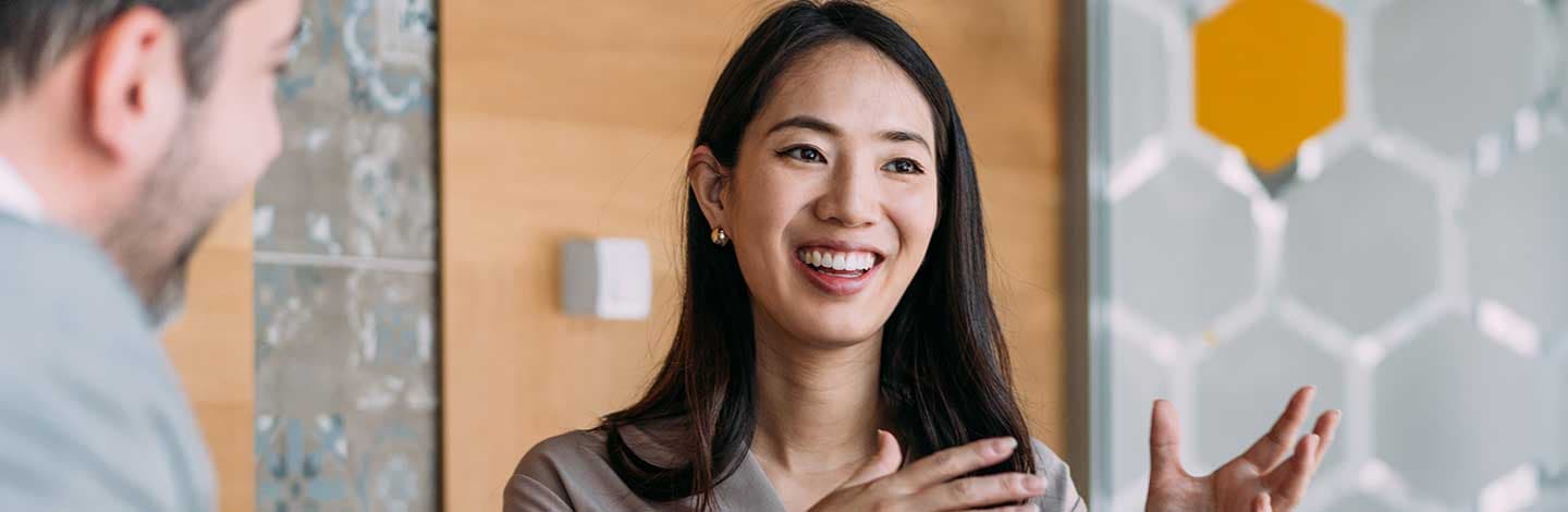 Person smiling during conversation in modern office with wooden wall and hexagonal glass design elements.