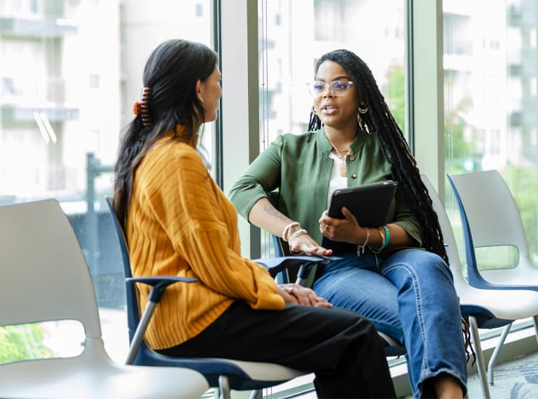 An attentive young woman listens as she receives advice from a caring female counsellor.