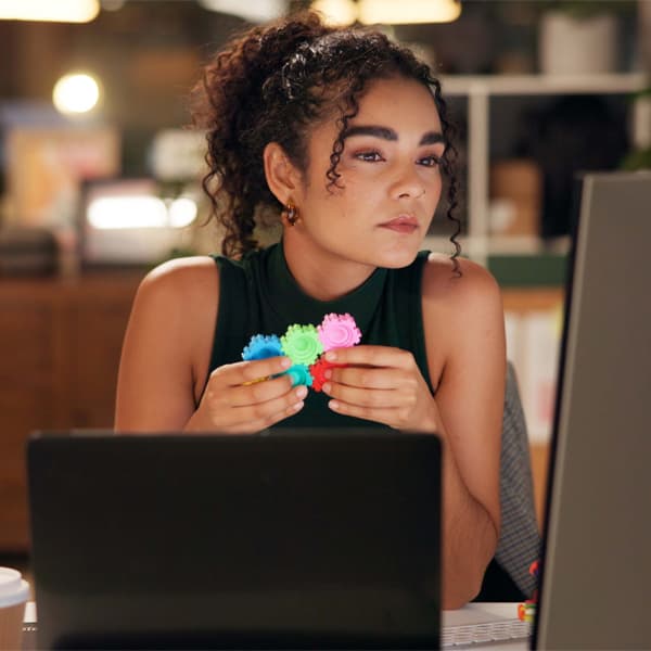 Business woman, laptop and thinking with pop toy, creative agency and ideas for night brainstorming. Girl, brand consultant and multi screen computer with project, proposal and office fidget spinner.