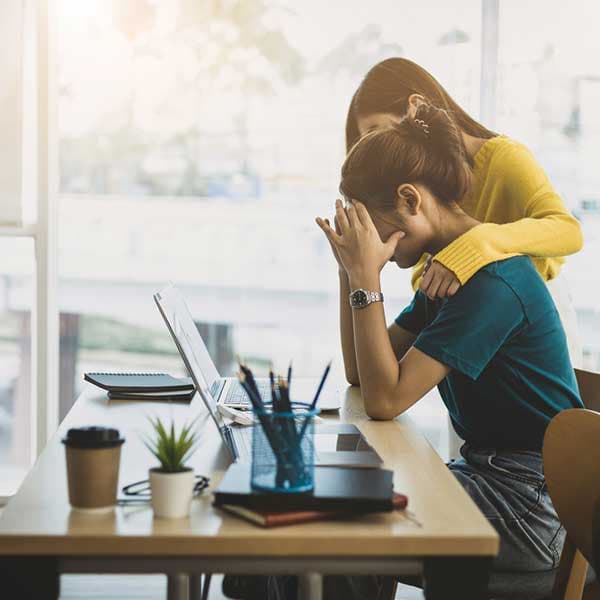 Female team member with arm around another team member at work